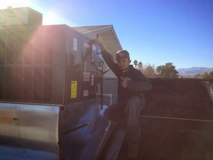 HVAC technician performing Heat Pump Repair on a rooftop unit in Bellwood